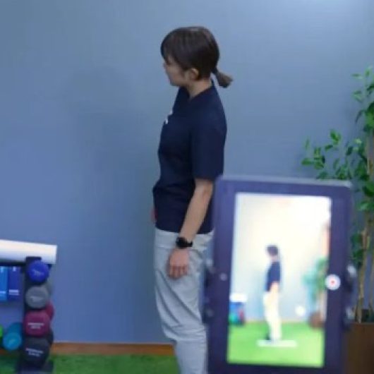 撮影した動きをタブレットで確かめるトレーナー